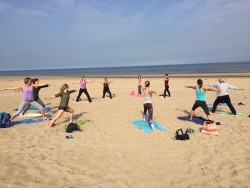 De yogagroep in krijgerhouding op het strand van Wassenaar