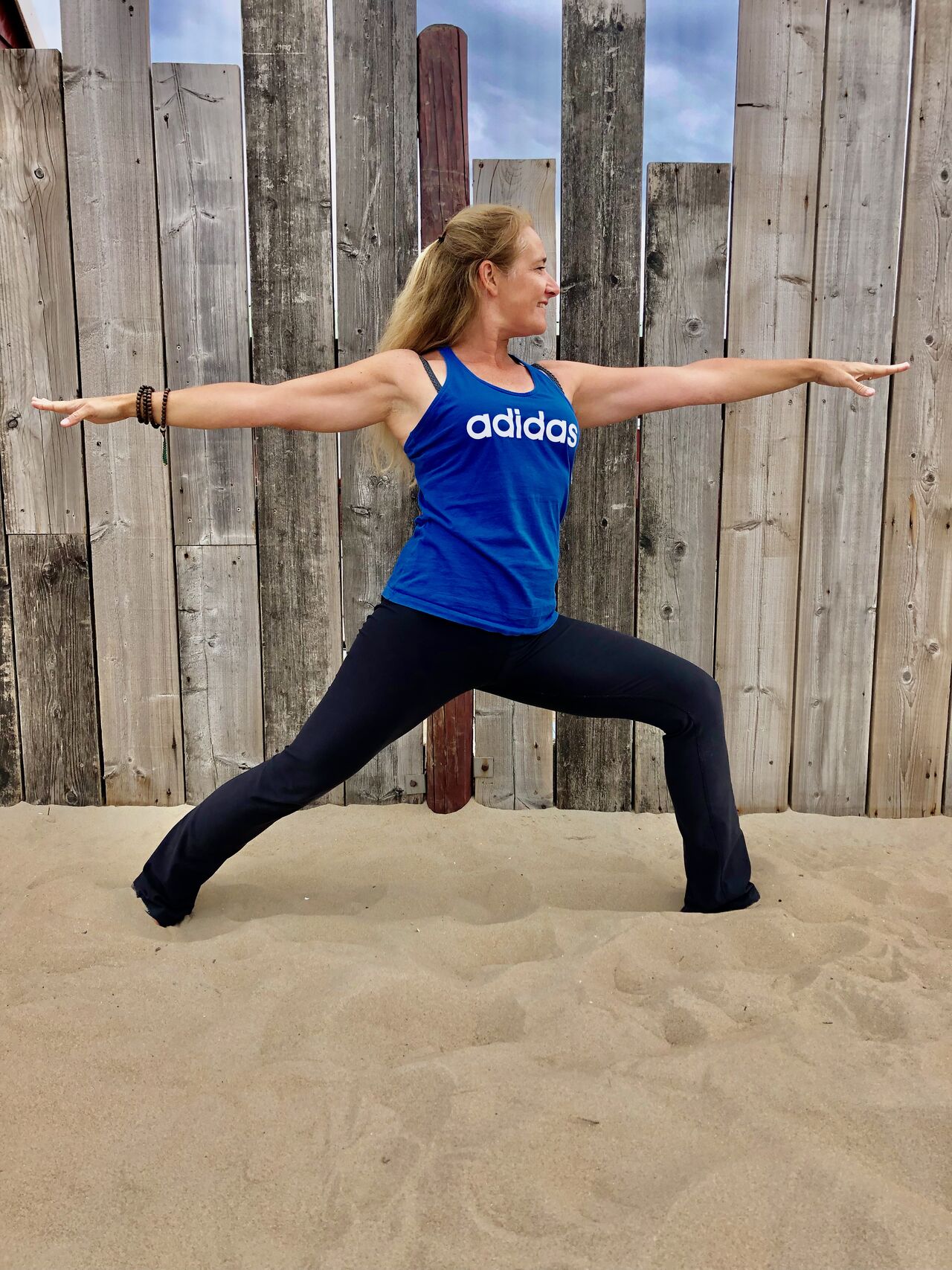 Caroline van den Ende in krijgerhouding op het strand, voor een houten schutting
